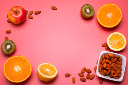 Fruits and nuts on the pink background. Orange, lemon, kiwi, apple. Free space for text.の写真素材