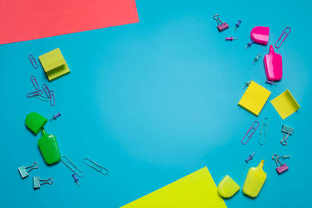 Stationery items on the blue background with free space for text. Creative, colorful background with scool or office supplies. Flatlay with copy space, top view. Markers, paper clips, sticky notes.の写真素材