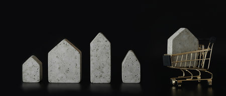 House model in mini shopping cart on the black background. Buy a house. Concept for property ladder, mortgage and real estate investment.の写真素材