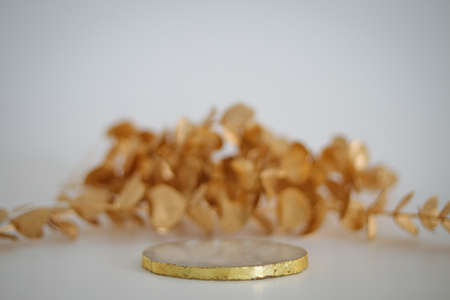 Marble podium with golden leaves on the white background. Podium for product, cosmetic presentation. Creative mock up. Pedestal or platform for beauty products.の写真素材