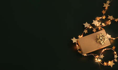 Christmas composition. Xmas background. Christmas gift and decoration elements on the dark background, fairy lights. Free space for text, copy space. Flat lay, top viewの写真素材
