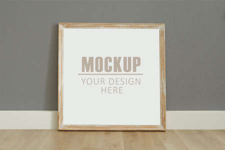 Frame, poster mock up with wooden frame. Empty frame standing on the wooden floor, grey wall. Free...