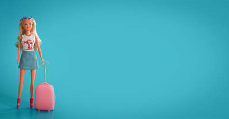 Doll with suitcase. Travel and flights, vacation and holidays. Free space for text, copy space. Colorful design.の写真素材