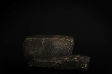 Rock podium on the black background. Stone podest for product, cosmetic presentation. Creative mock up. Pedestal or platform for beauty products.の写真素材