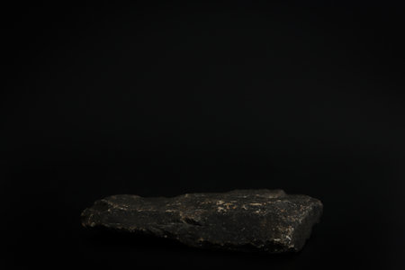 Rock podium on the black background. Stone podest for product, cosmetic presentation. Creative mock up. Pedestal or platform for beauty products.の写真素材