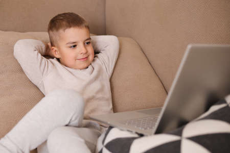 Child at home watching cartoon on the computer. Little boy and a laptop. Modern kid and education technology.の写真素材
