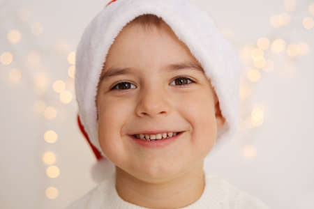 Smiling little boy with Christmas lights on the white background. Happy child, Christmas celebration, Xmas time.の写真素材