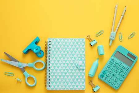 Blue stationery items on the yellow background with free space for text. Creative, colorful...