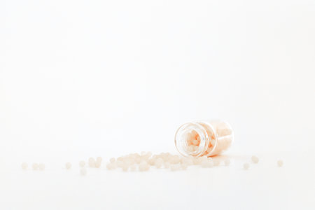 Close-up image of homeopathic globules in glass bottle on white background. Homeopathy pharmacy, herbal, natural medicine, alternative homeopathy medicine, healthcare. Free space, copy space.の写真素材
