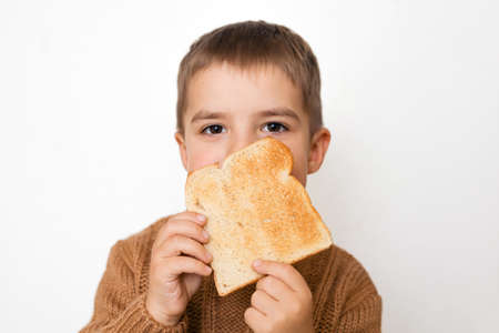Children and gluten. Preschool boy with toasted bread. Gluten intolerance by kids. Copy space on bread for text or symbol.の写真素材