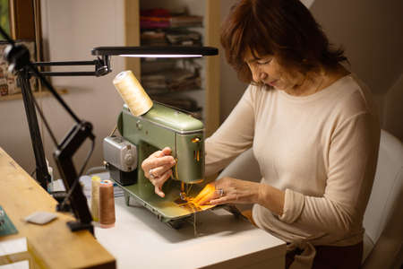 Woman sewing fabric with a vintage, retro sewing machine. Fashion, creation and tailoring. Process...