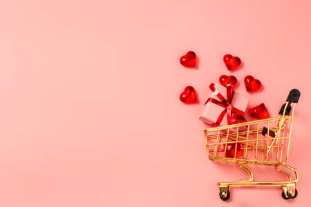 Shopping cart, trolley with little gift box and hearts on pink background with free space for text, copy space. Valentines Day, sale.の写真素材