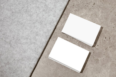 Blank white business cards on rough concrete surface. Mockup for branding identity. Two stacks, to show both sides of card. Template for graphic designers. Free space, copy space.の写真素材