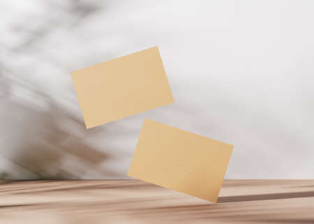Blank brown cardboard business cards with plants shadows on the white background. Natural mockup for branding identity. Two cards to show both sides. Template for graphic designers. 3D rendering.の写真素材