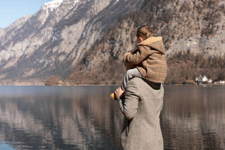 Father and son enjoying mountains, snow, lake, good weather, blue sky, sun. Little boy and his father spending time together. Family time. Beautiful landscape. Tourism, holiday, travel. Amazing view.の写真素材
