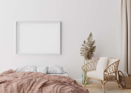Empty picture frame on white wall in modern bedroom. Mock up interior in boho style. Free, copy...