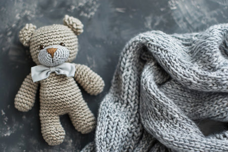 Cozy knitted teddy bear with a gray bow, perfect for baby shower invites, newborn gifts, nursery decor, and warm, handcrafted product themes with space for text. Generative AIの素材