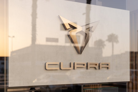Torrevieja, Spain - 09-07-2024: Cupra logo, highlighted by golden hues of a setting sun. Ideal for automotive branding, marketing materials, and editorial content on modern car brands.のeditorial素材