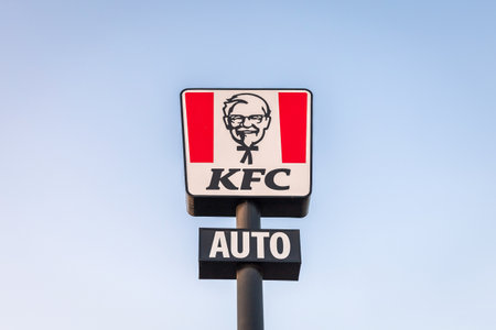 Torrevieja, Spain - 09-07-2024: iconic KFC sign mounted on a pole against a clear blue sky, highlighting the brands recognizable logo. Kentucky Fried Chicken.のeditorial素材