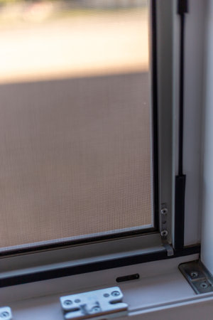 Brightly lit indoor space features a close-up of a meticulously crafted window frame and screen, showcasing quality materials designed for effective fly protectionの写真素材