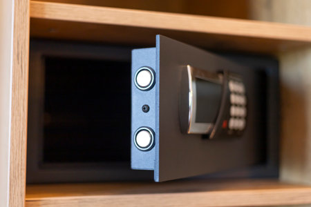 A secure safe with a digital keypad is partially open in a wooden cabinet. The safe has two circular buttons for operation and appears modern and functionalの写真素材