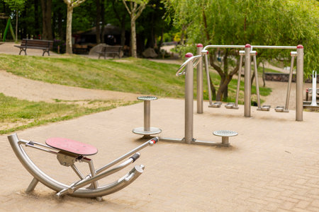 Various outdoor fitness machines are set up in a serene community park, providing a space for exercise and wellnessの写真素材