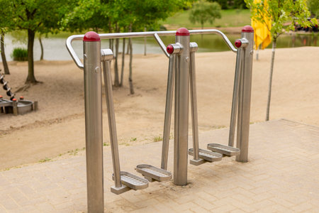 A set of outdoor fitness equipment designed for leg workouts is positioned alongside a peaceful park...