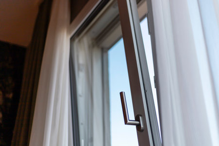A partially open window allows a glimpse of the clear blue sky, with soft curtains framing the sunlight. The interior feels cozy and inviting, perfect for relaxationの写真素材
