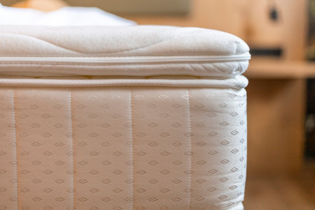 A well-crafted mattress is positioned neatly in a warm and inviting bedroom, showcasing its quilted fabric and attention to detail. A peaceful atmosphere promotes relaxationの写真素材