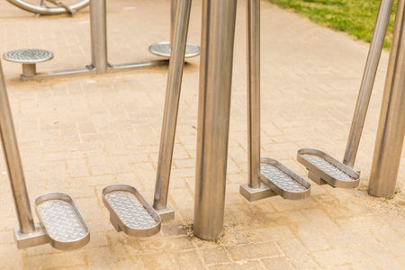 Sturdy metal fitness equipment is positioned in an outdoor park area, showcasing pedals designed for...