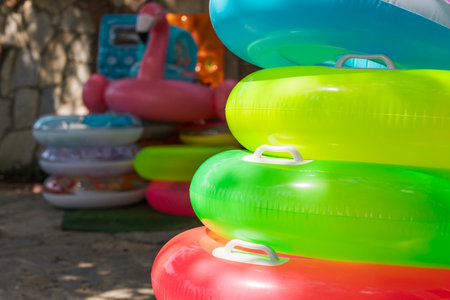 Brightly colored pool floats are stacked in a relaxing outdoor setting, showcasing a cheerful...