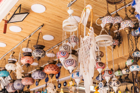 A variety of intricately designed lanterns and crafts hang from the ceiling in a bustling market in...