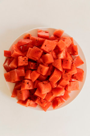 A plate filled with vibrant red watermelon cubes showcases the abundant, juicy fruit, perfect for a...