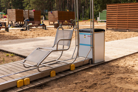A specially designed sliding chair is placed on a wooden pathway at a beach, providing a seamless way for disabled users to access the sea comfortably and safelyの写真素材