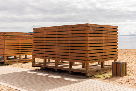 Wooden changing cabins are situated near the beach, offering a private space for beach visitors. The...