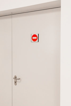 A closed door features a red no entry sign clearly positioned above the handle, signaling restricted...