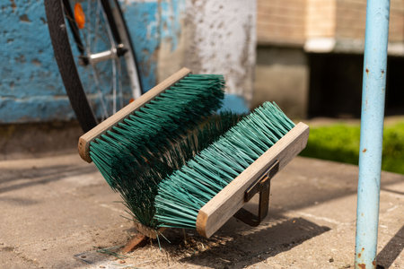 Outdoor shoe cleaning brushes mounted on a concrete surface. Green bristles with wooden base, designed for cleaning dirt and mud from shoes. Practical cleaning tool for public or private use.の写真素材