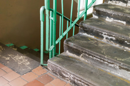 Staircase shows significant wear with chipped steps and peeling paint, reflecting the buildings age...