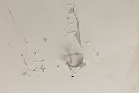 An old building displays significant deterioration with cracks in the walls and peeling paint. This...