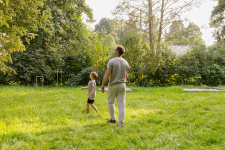 Father and his young child explore a lush playground, surrounded by greenery, laughing and bonding...