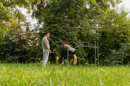 A father encourages his child as they play together on a playground. The child is attempting to...