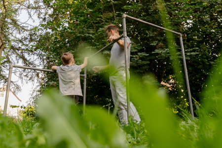 A father joyfully interacts with his young child at a playground surrounded by lush greenery on a...
