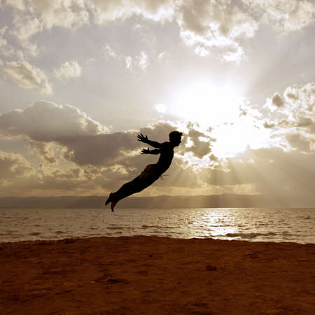 One person acrobatic jumping scene, look like Peter Pan is flying, symbolize vitality, aspiration, success, progress as well as fantasy, imagination, incentive, personal development, power, Agility and much moreScene is performed in front of the dead seaの写真素材