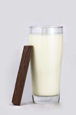Chocolate bar leaning at a glass of fresh milkの写真素材