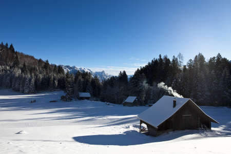 Rural sunny winter landscape with occupied log cabins in the mountainsの写真素材