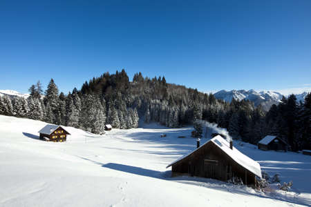 Rural sunny winter landscape with occupied log cabins in the mountainsの写真素材
