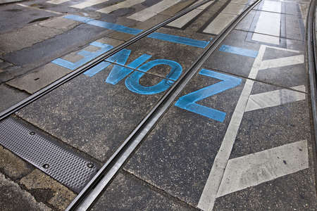road marking  zone  in vibrant blue letters on asphalt surface with rails after some rain の写真素材