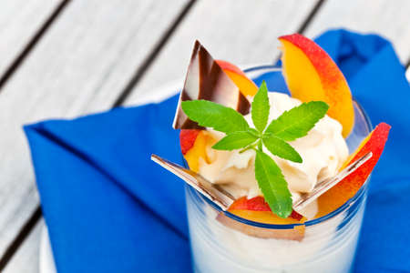 Sweet tasty cream in glass topped with slice of fruits, chocolate and mint on the wooden tableの写真素材