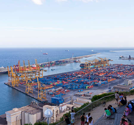 Some people take a rest at the hill Montjuic with a view at the industrial part of the Port of Barcelona.の写真素材