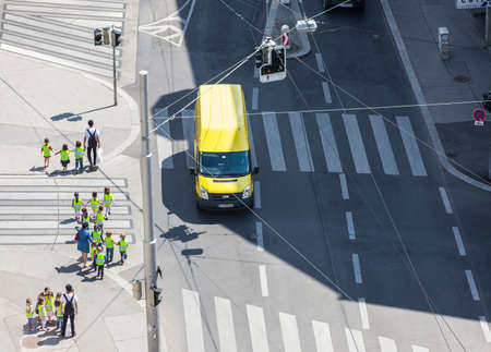 Some unrecognizable preschooler with their teachers crossing the street at a sunny dayのeditorial素材